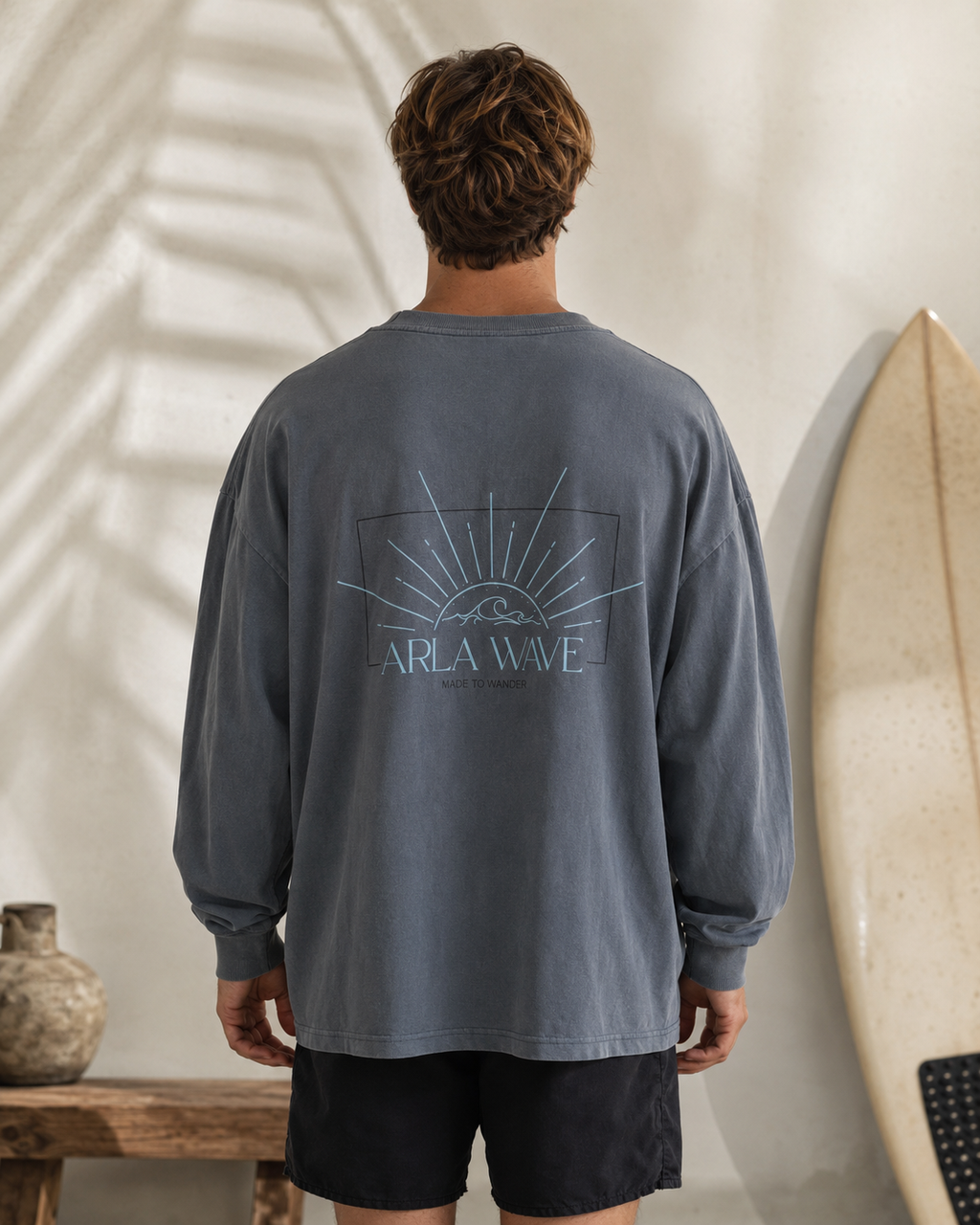 Arla Wave navy oversized long sleeve shirt back view on masculine model, large light blue logo with sun and waves