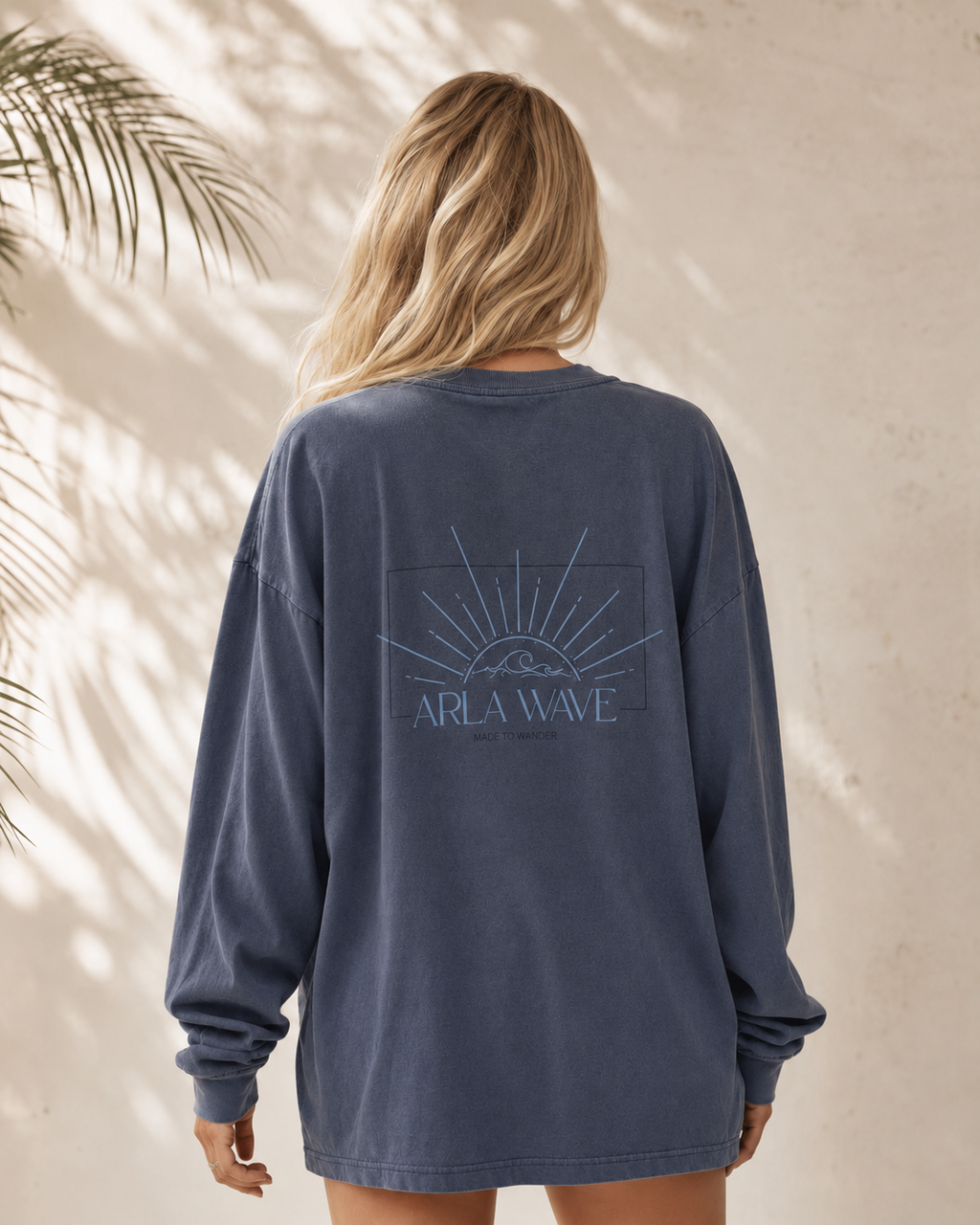Back view of model wearing the Arla Wave vintage navy oversized long-sleeve shirt, featuring a longline fit, extra-long sleeves and large blue Arla Wave back artwork.